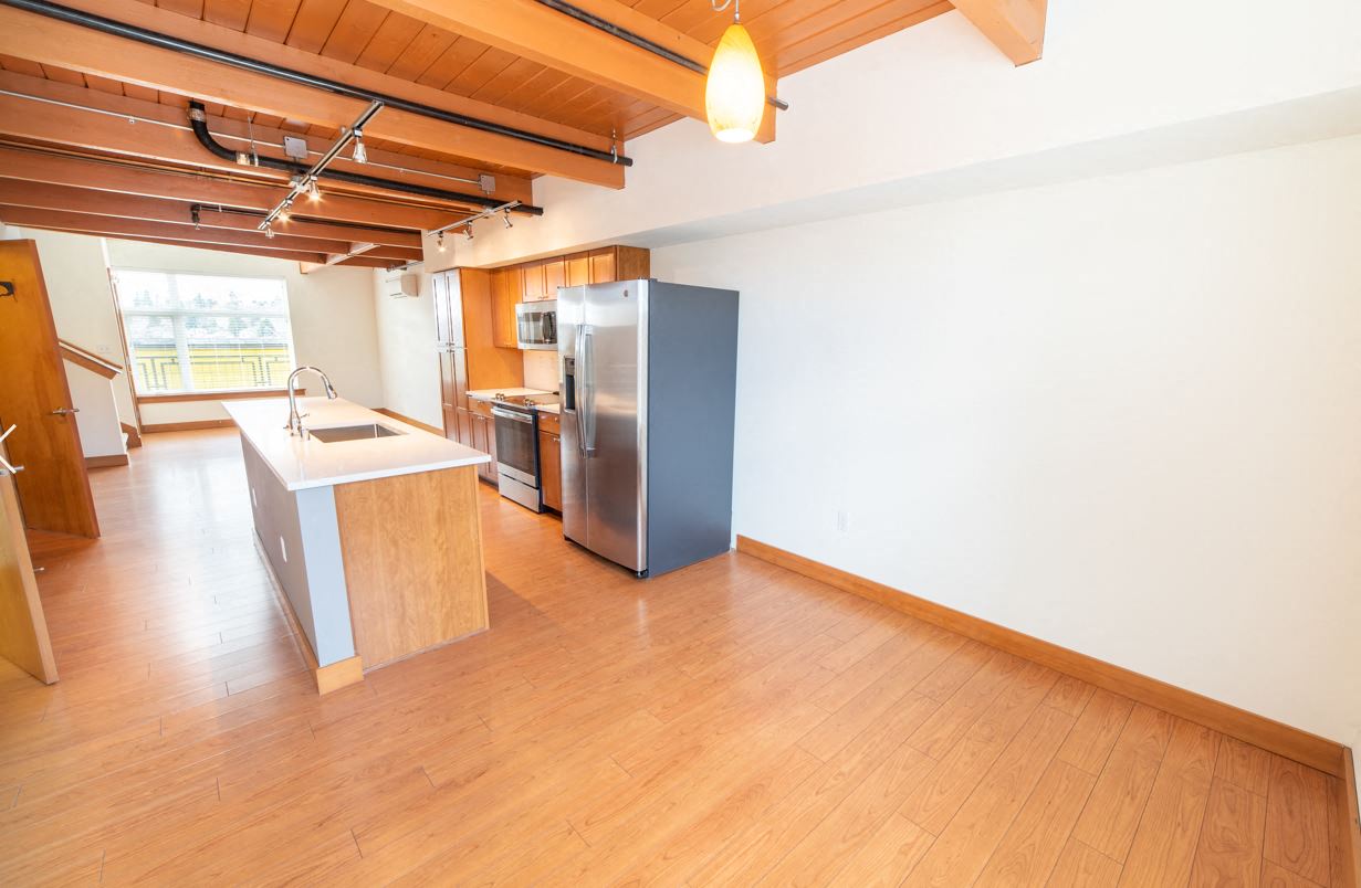 a kitchen with a stainless steel refrigerator in a large room