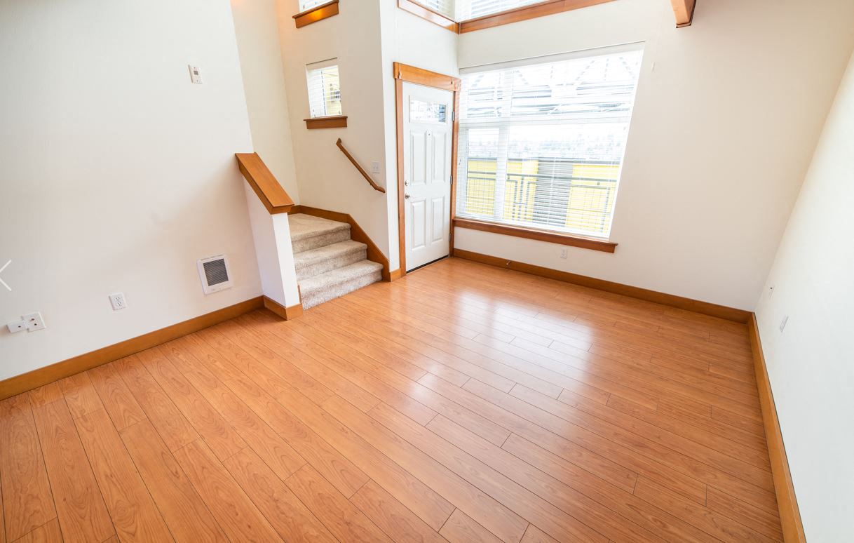 a living room with a hard wood floor and a door to a staircase