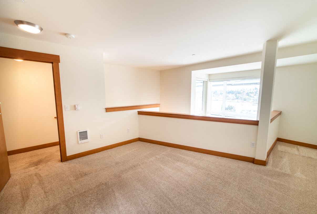 an empty living room with a window and carpet