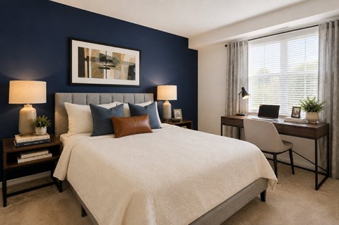 A bedroom with a large bed, a desk with a chair, and a painting on the wall.