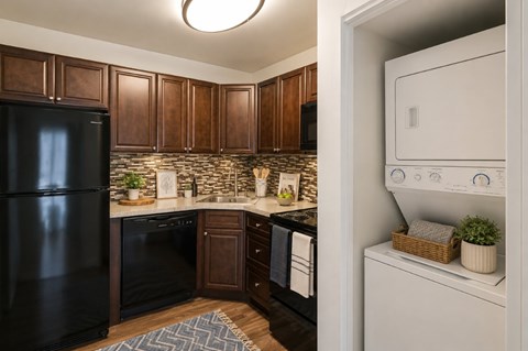 A black refrigerator is in a kitchen with brown cabinets.