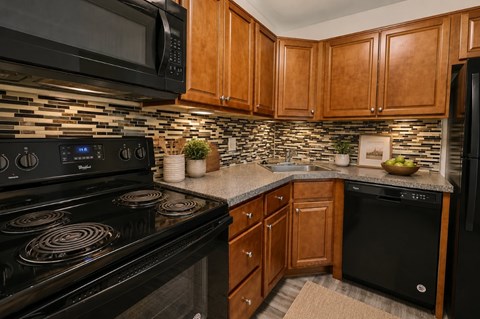 A kitchen with black appliances and wooden cabinets.