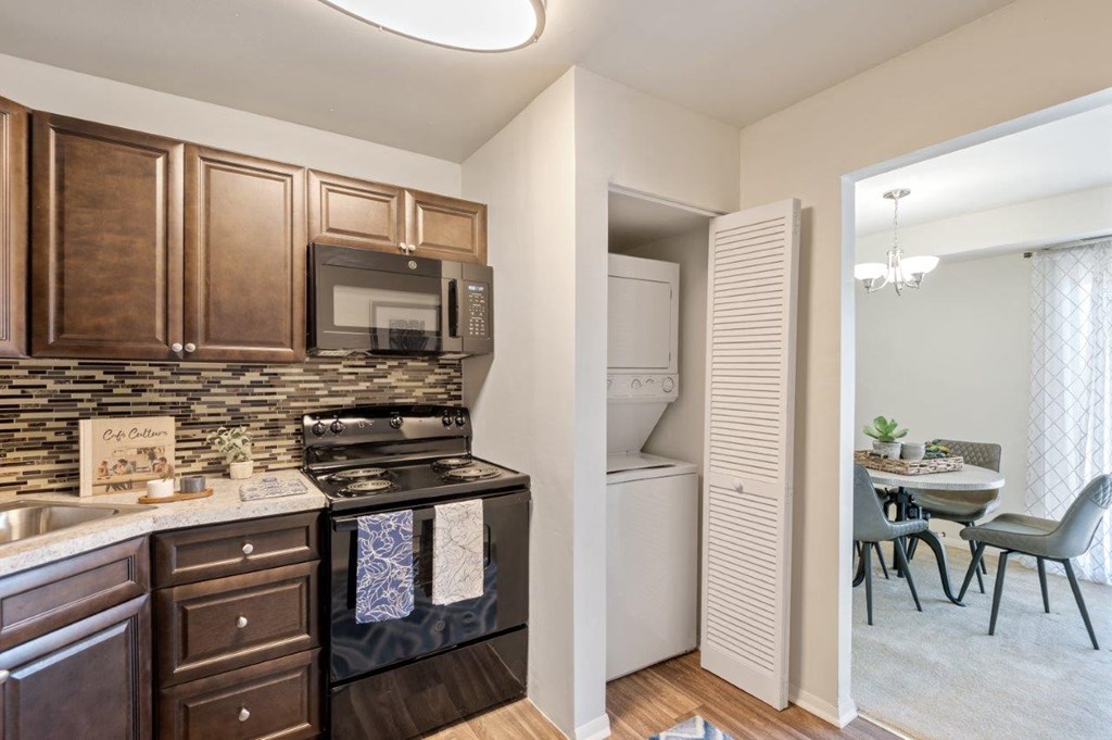 a kitchen with a stove and microwave and a dining room with a table and chairs