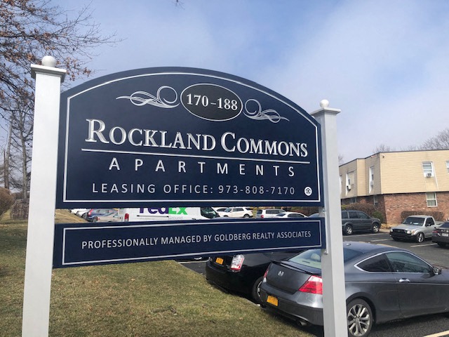 a sign common apartments with cars parked in a parking lot