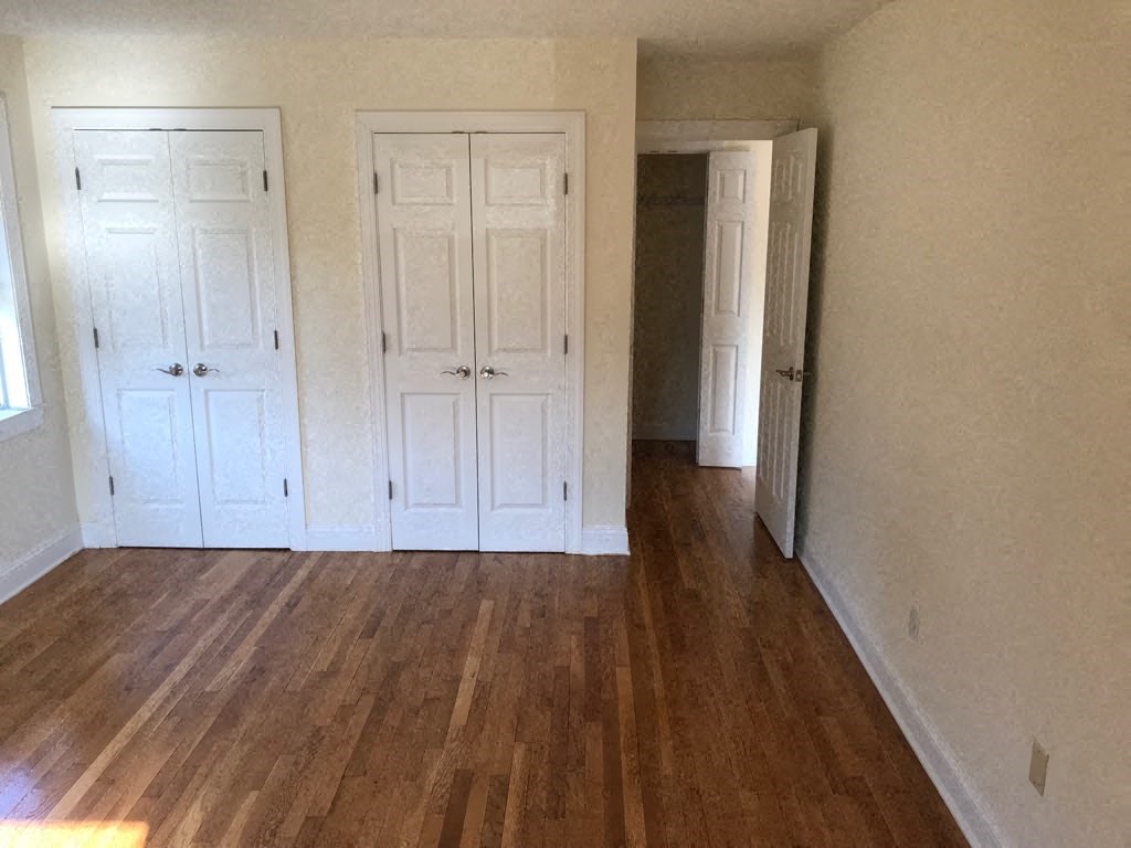 a empty room with three doors and a wood floor
