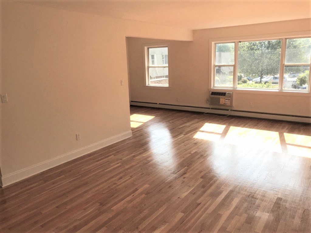 an empty living room with wooden floors and two windows