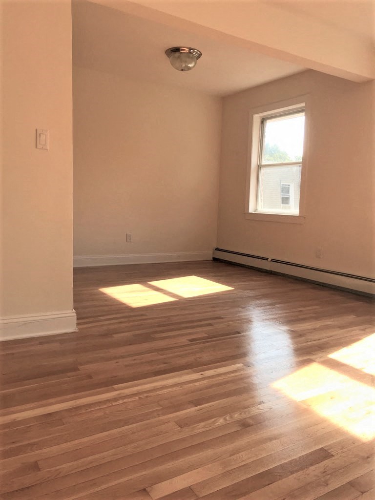 an empty living room with wooden floors and a window
