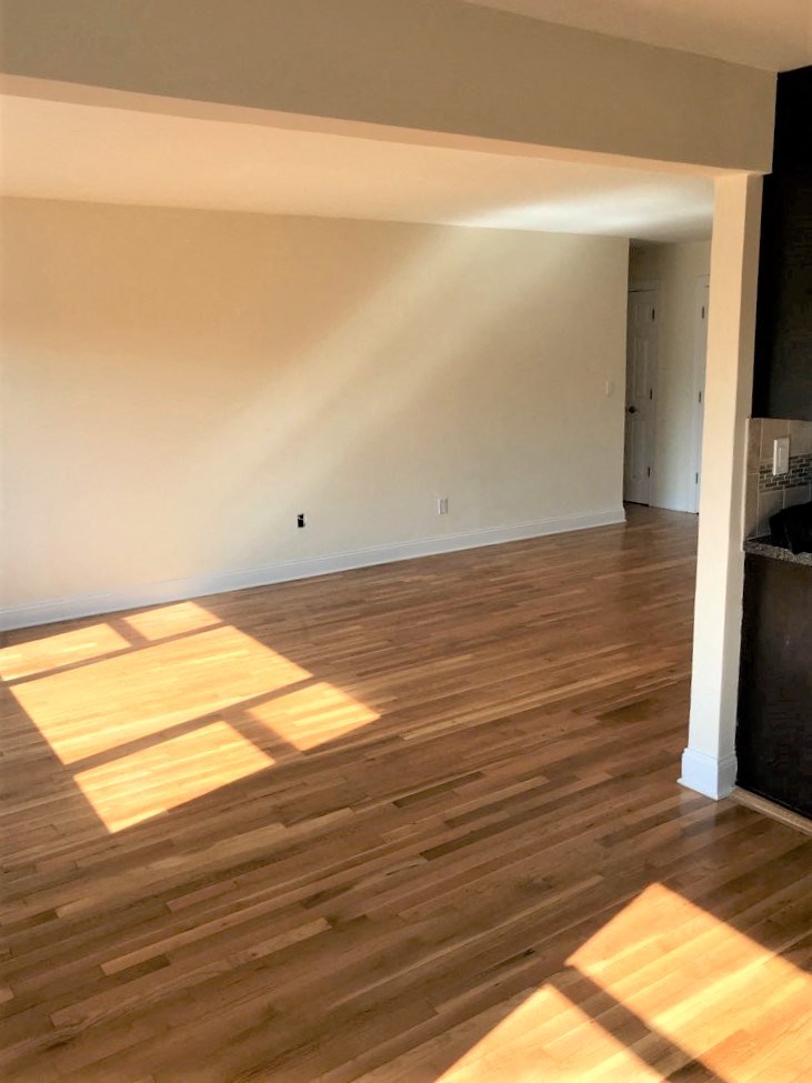 an empty living room with wooden floors and white walls