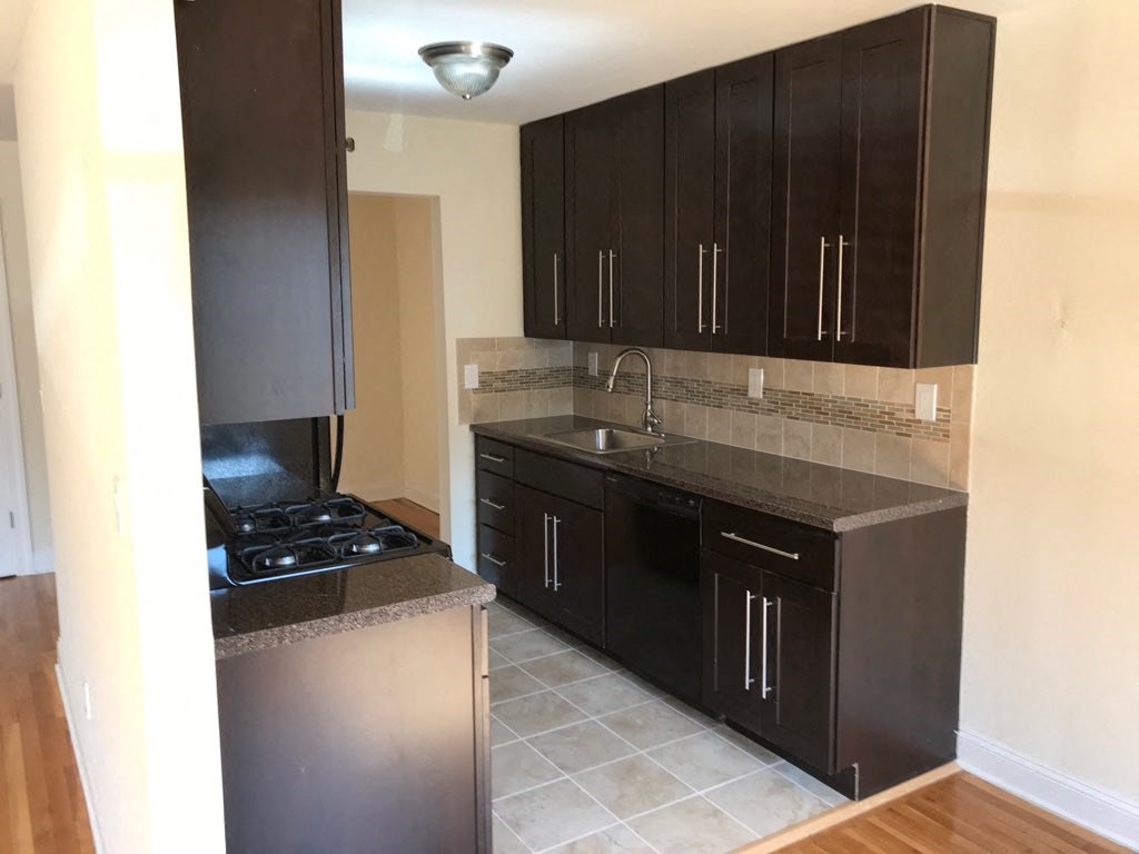 an empty kitchen with black cabinets and a sink