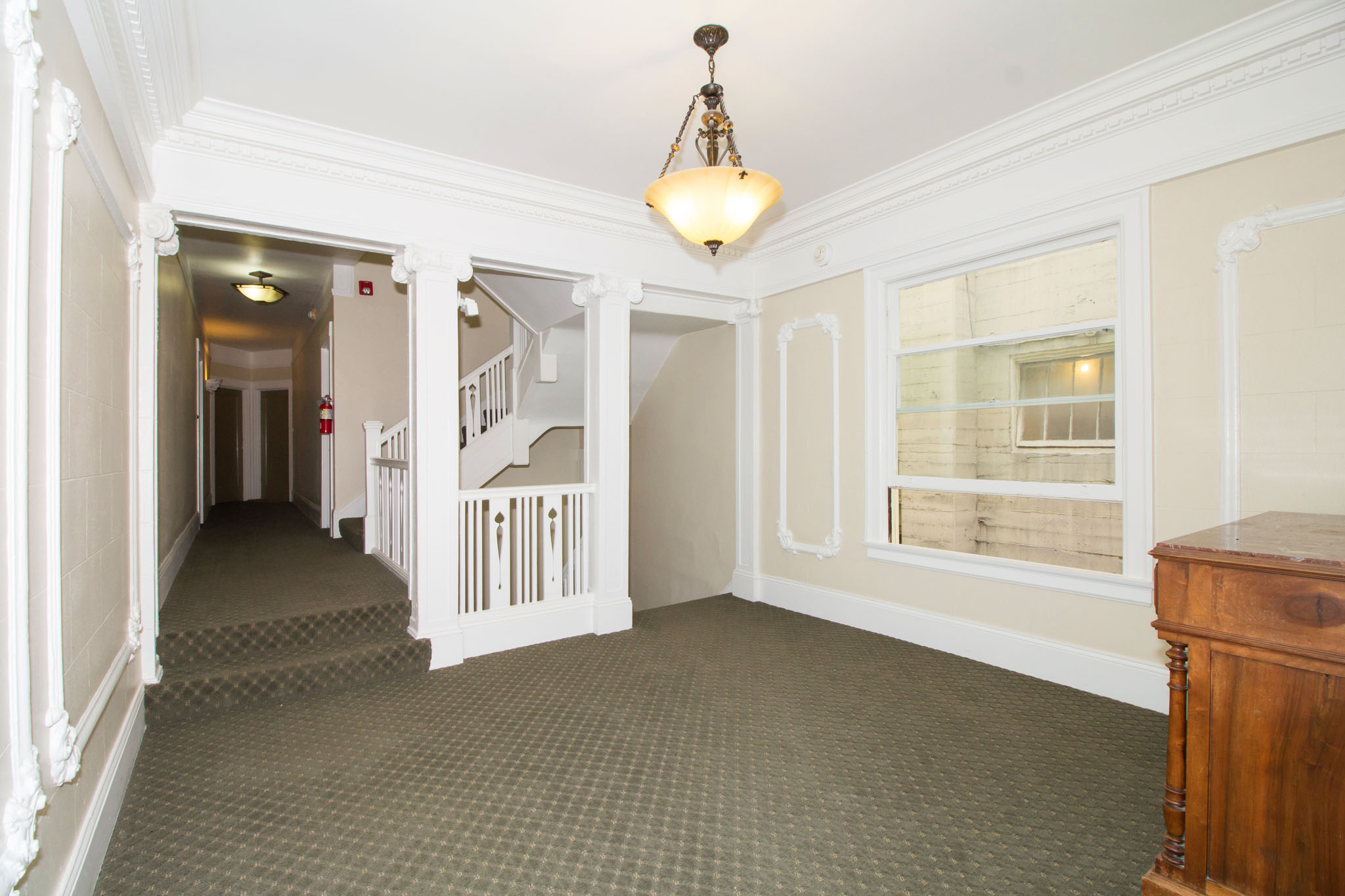A hallway with a staircase and a chandelier.