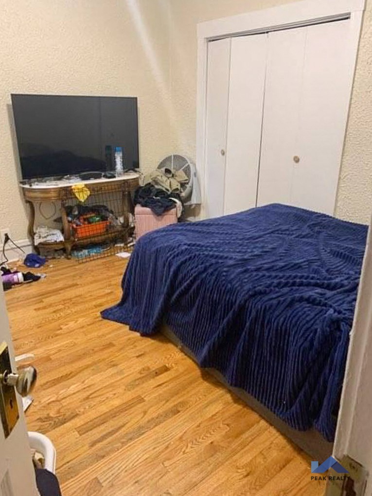 a man in a bedroom with a bed and a tv