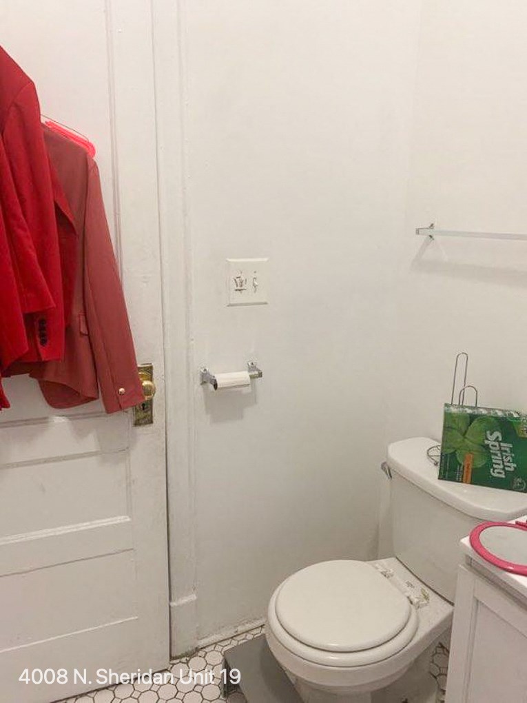 a white bathroom with a toilet and a red jacket