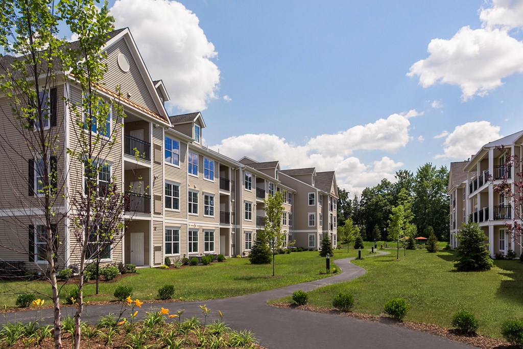 an exterior view of an apartment building with grass and trees
