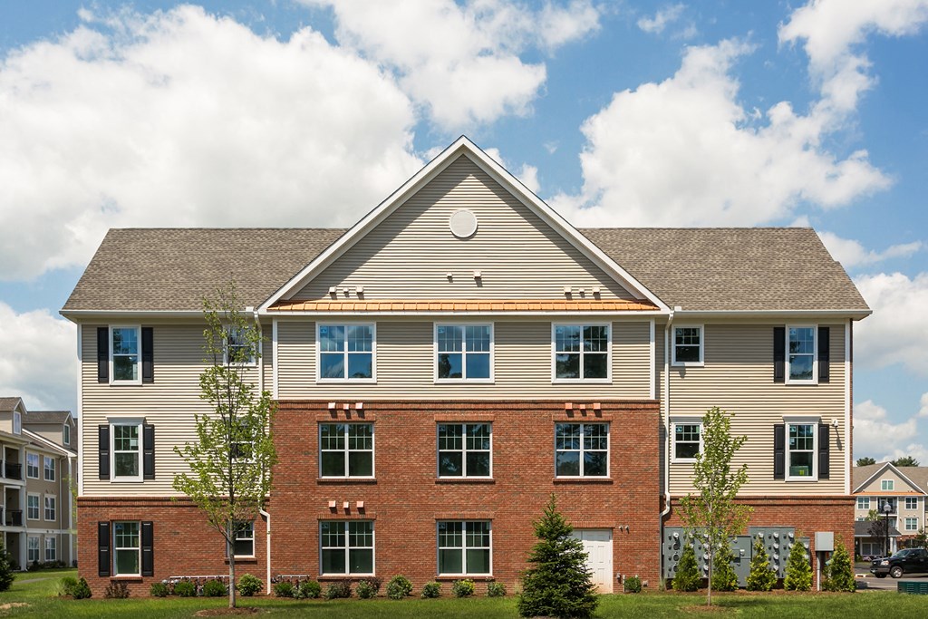 a large brick house with tan siding and a gray roof