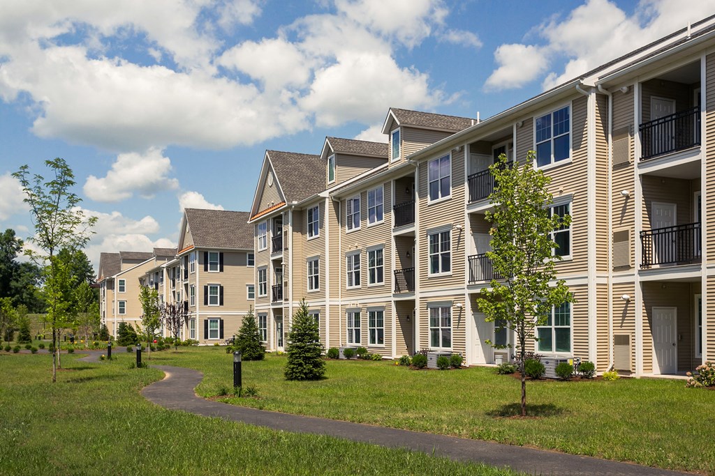 an exterior view of an apartment building with grass and trees