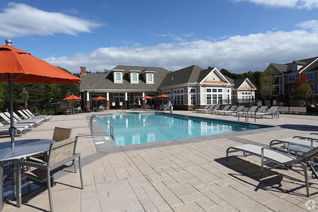 a swimming pool with chairs and umbrellas at the resort on a sunny day