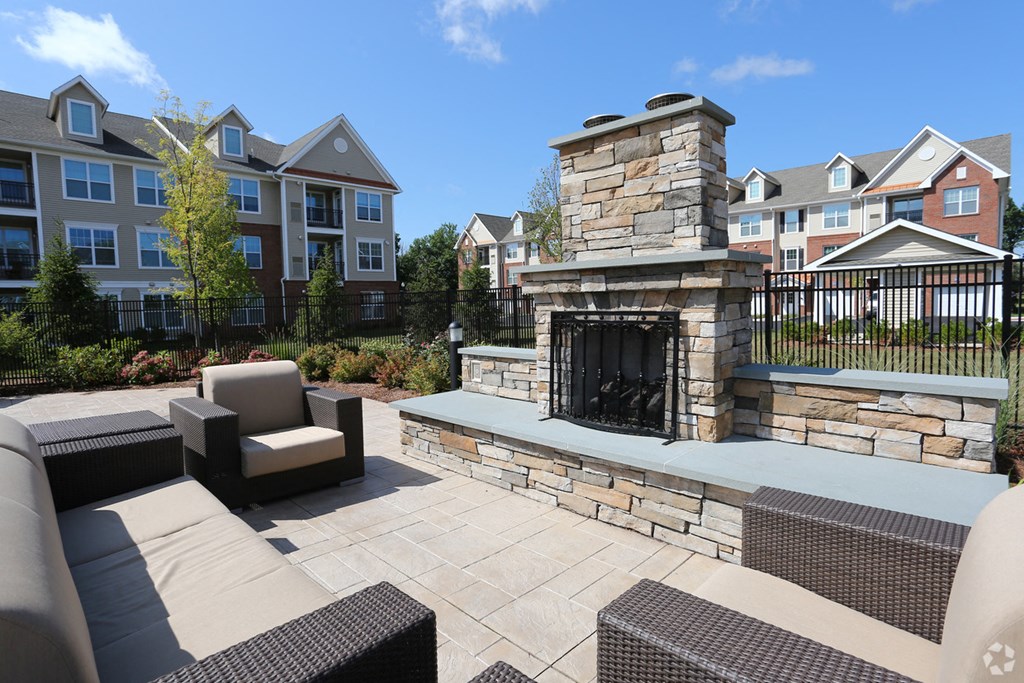 a patio with a stone fireplace and furniture in front of an apartment building