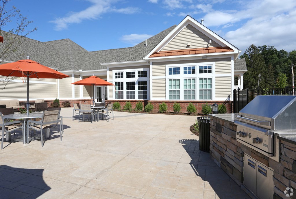 a patio with a grill and umbrellas in front of a house
