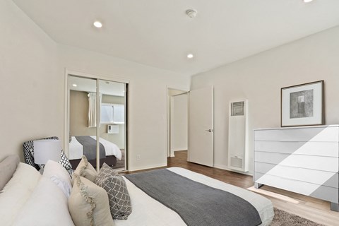 A bedroom with a large bed and a mirror on the wall.