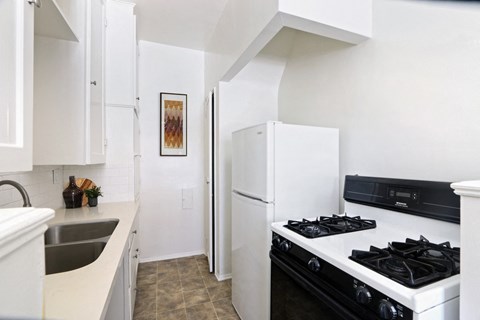 A kitchen with a black stove top oven and a white refrigerator.