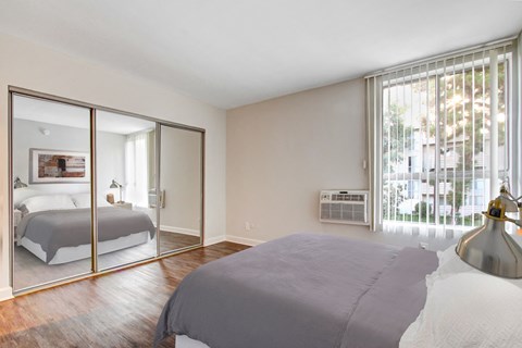 A bedroom with a large bed and a mirrored closet door.