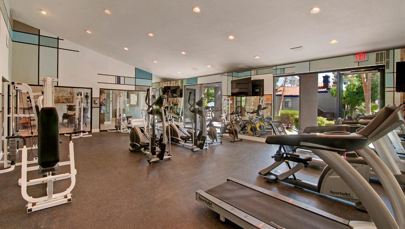 a gym with cardio equipment and glass windows
