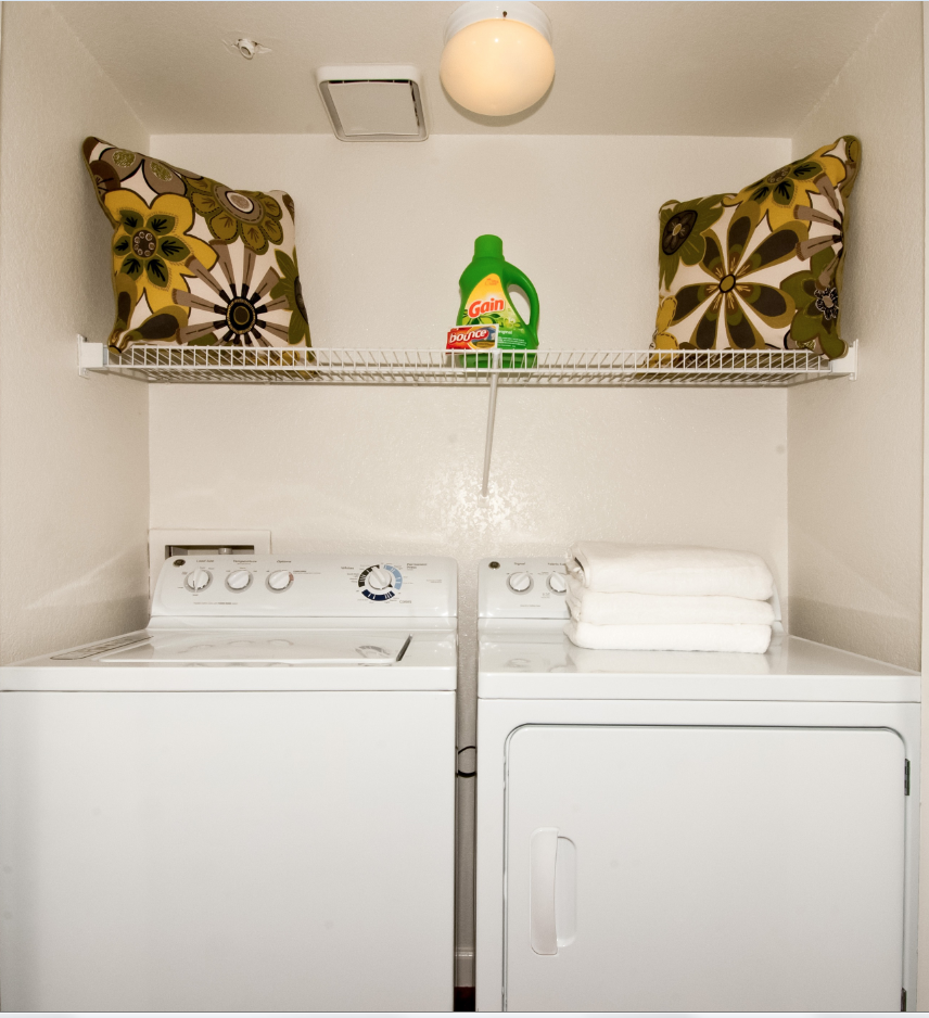 a white washer and dryer in a small laundry room with a shelf above