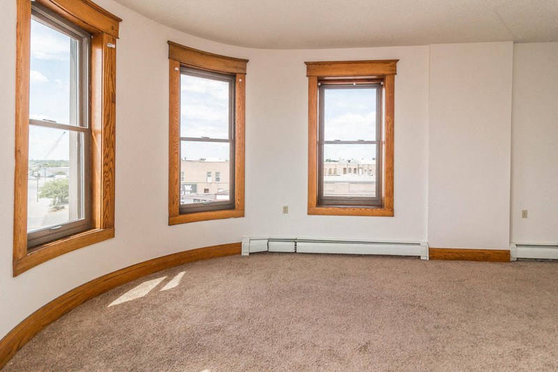an empty room with three windows and a carpeted floor