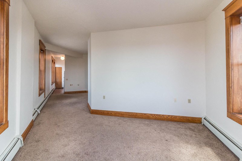 a living room with a white wall and a carpeted floor