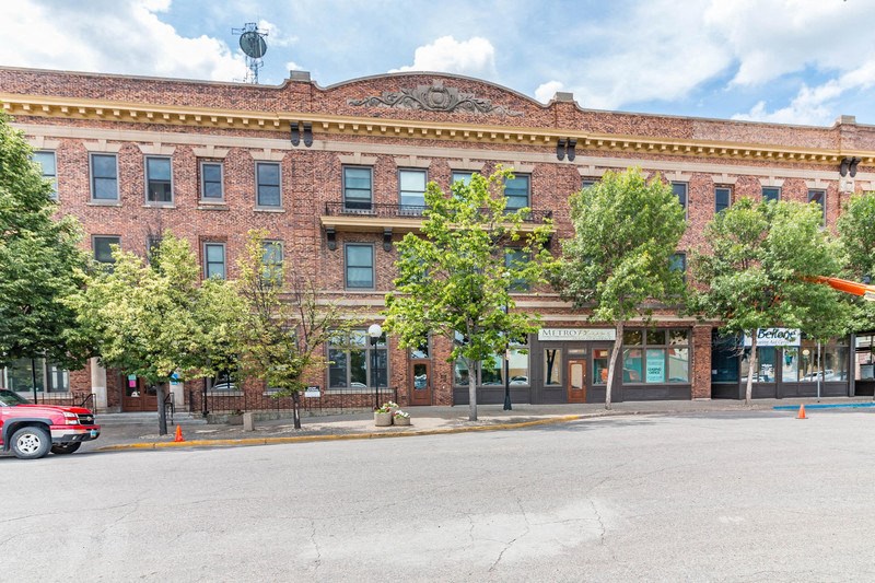 a brick building with trees in front of it on a street