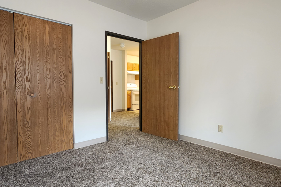 a bedroom with two doors and a hallway to a bathroom