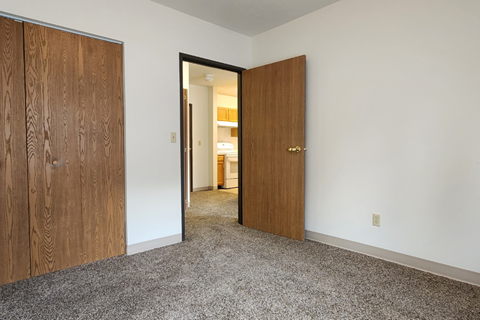 a bedroom with two doors and a hallway to a bathroom