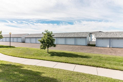 a row of white garages with a sidewalk and grass