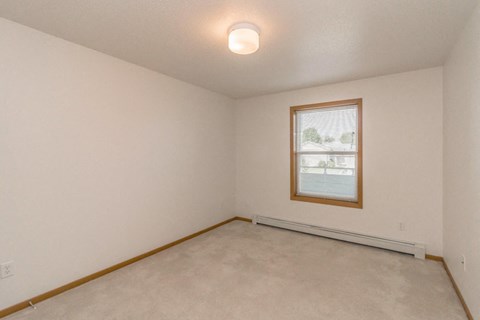 the living room of an empty home with a window and white walls