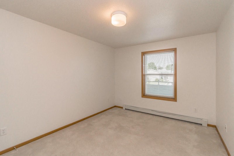 the living room of an empty home with a window and white walls