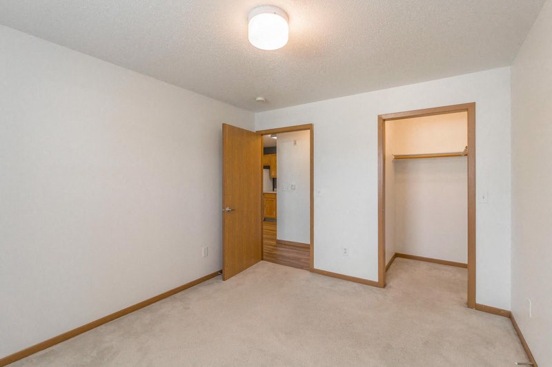 an empty living room with a door to a bathroom and a closet