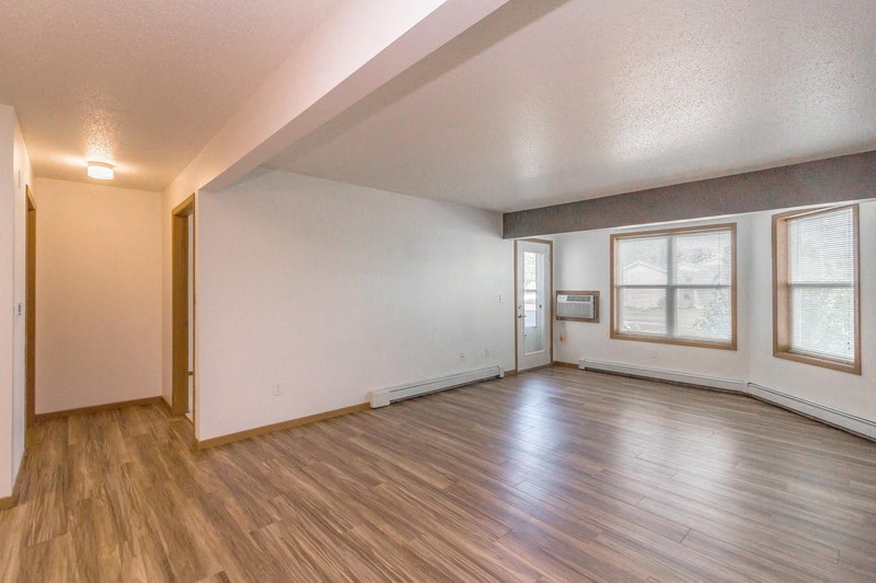 the living room and dining room of an empty house with wood floors and white walls