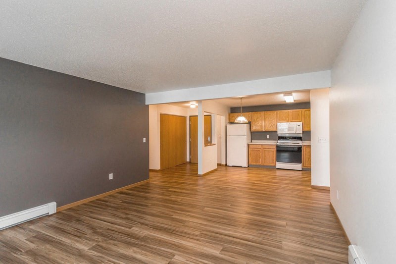 an empty living room and kitchen with wood floors