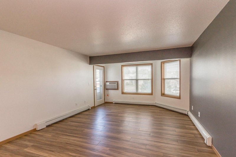 the living room of an empty house with wood floors and a window