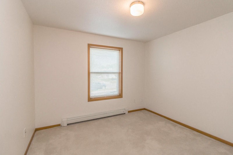 the living room of an empty house with a window and white walls
