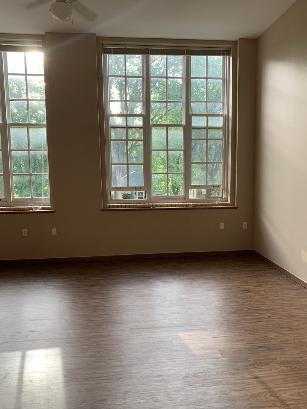 an empty living room with wood floors and large windows