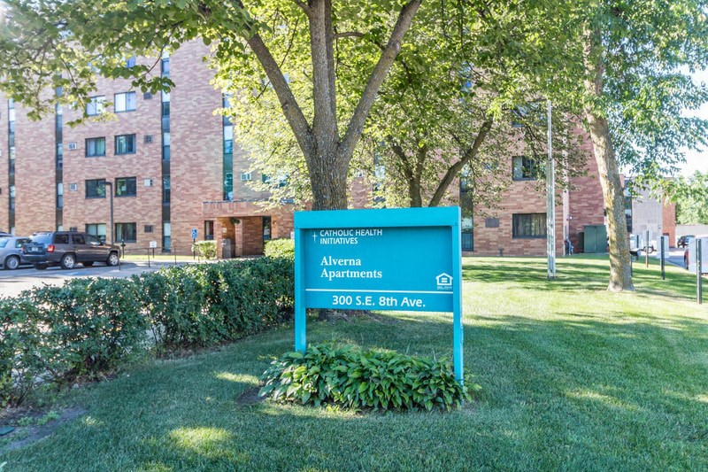 a blue sign in the grass in front of a building