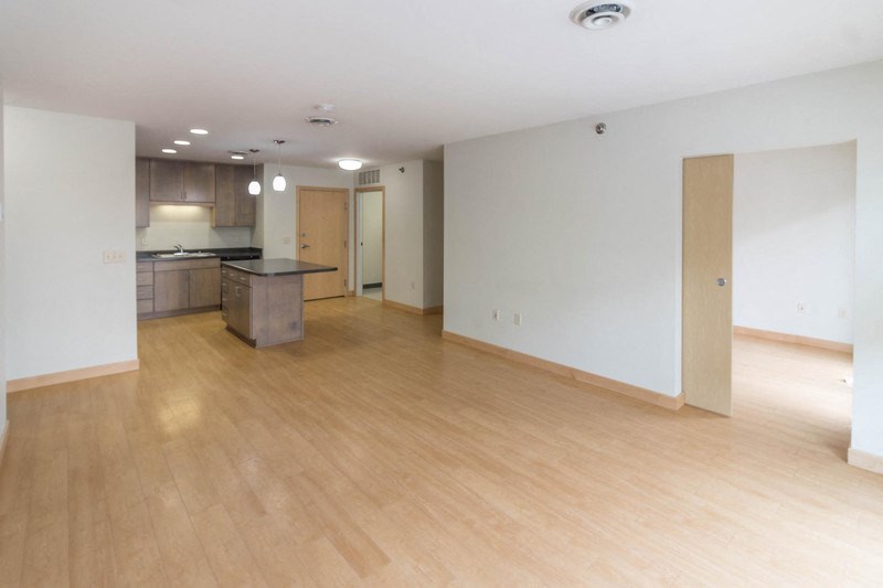 an empty living room and kitchen with wood floors