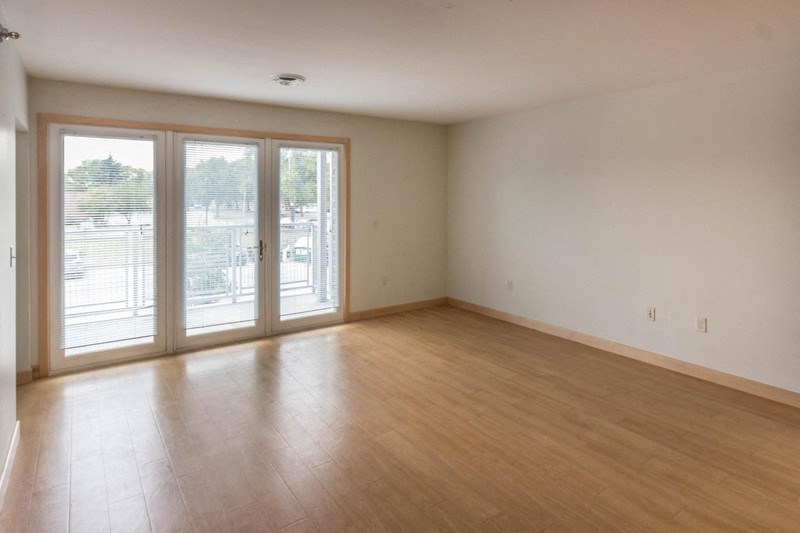 an empty living room with a wood floor and sliding glass doors