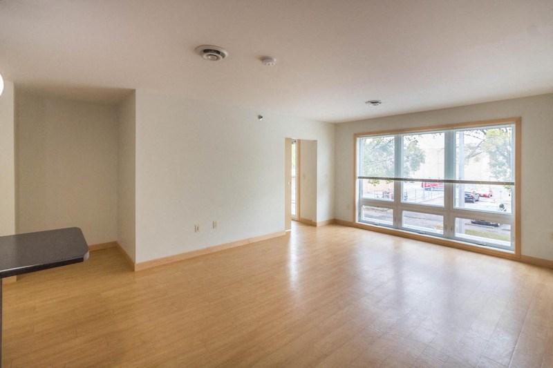 an empty living room with wood floors and a large window