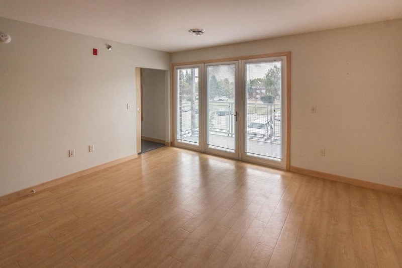 an empty living room with a wood floor and sliding glass doors
