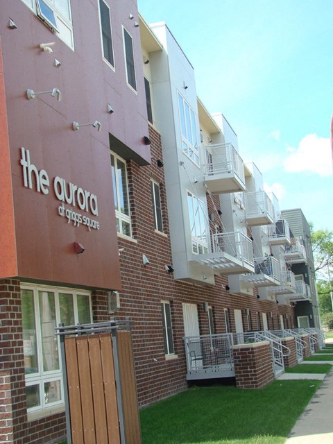 a brick apartment building with balconies and a sidewalk