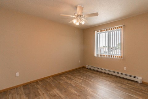an empty living room with a ceiling fan and a window
