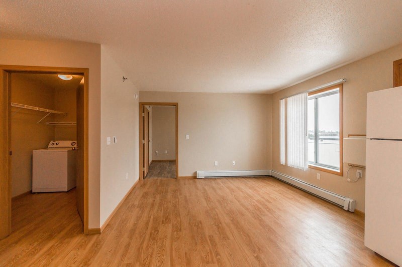 an empty living room and kitchen with a wood floor