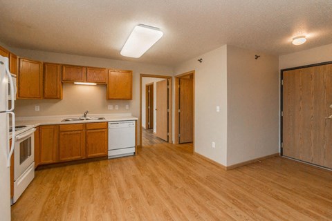 an empty kitchen with wooden floors and white appliances